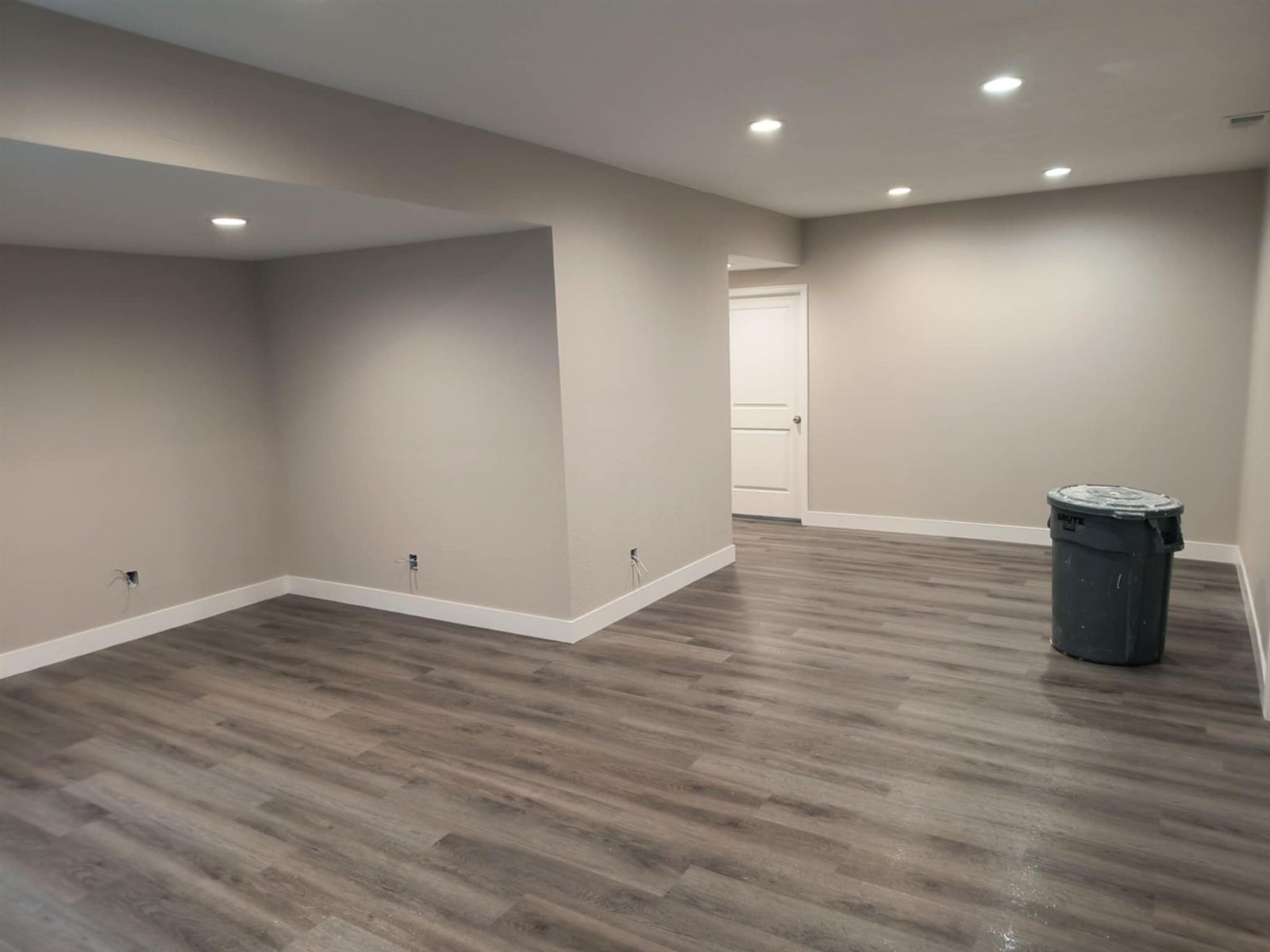 Finished basement with recessed lighting and vinyl plank flooring by Saw Dog Construction